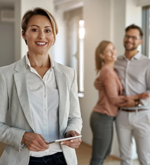 portrait-female-real-estate-agent-looking-camera-while-happy-couple-standing-background